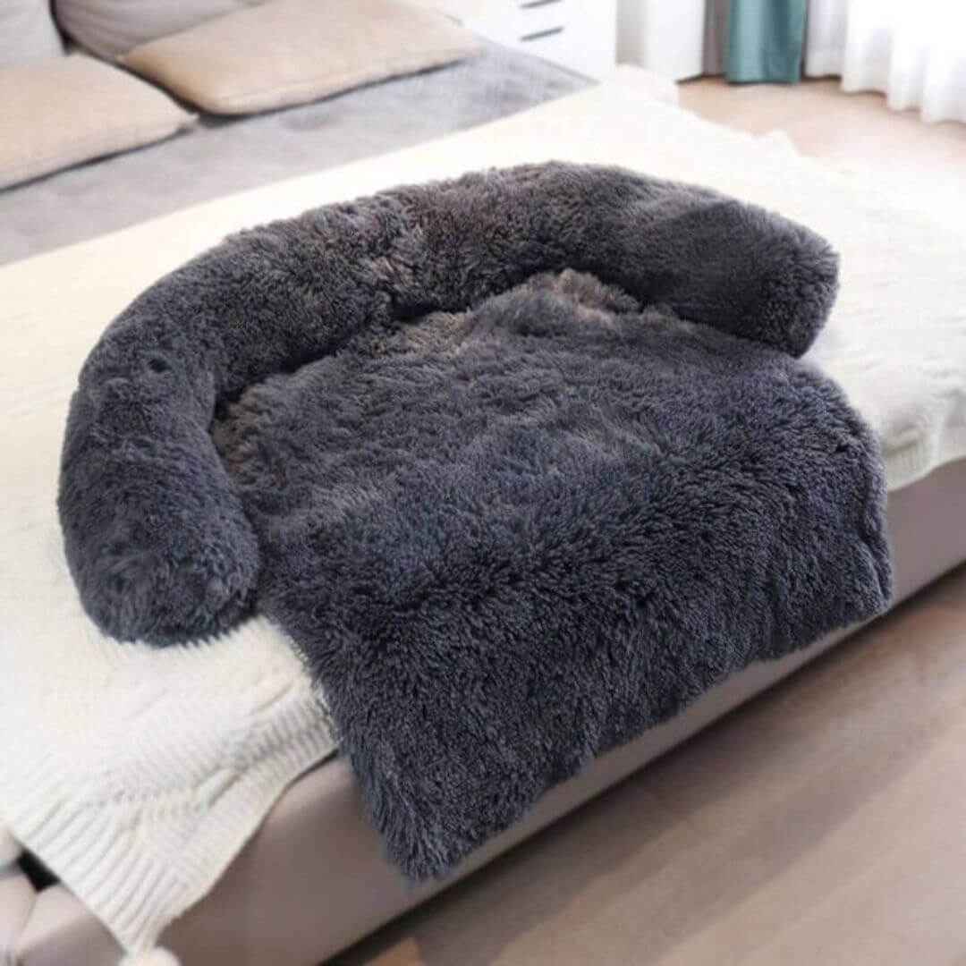 Soft and fluffy dark gray couch cover draped over a bed